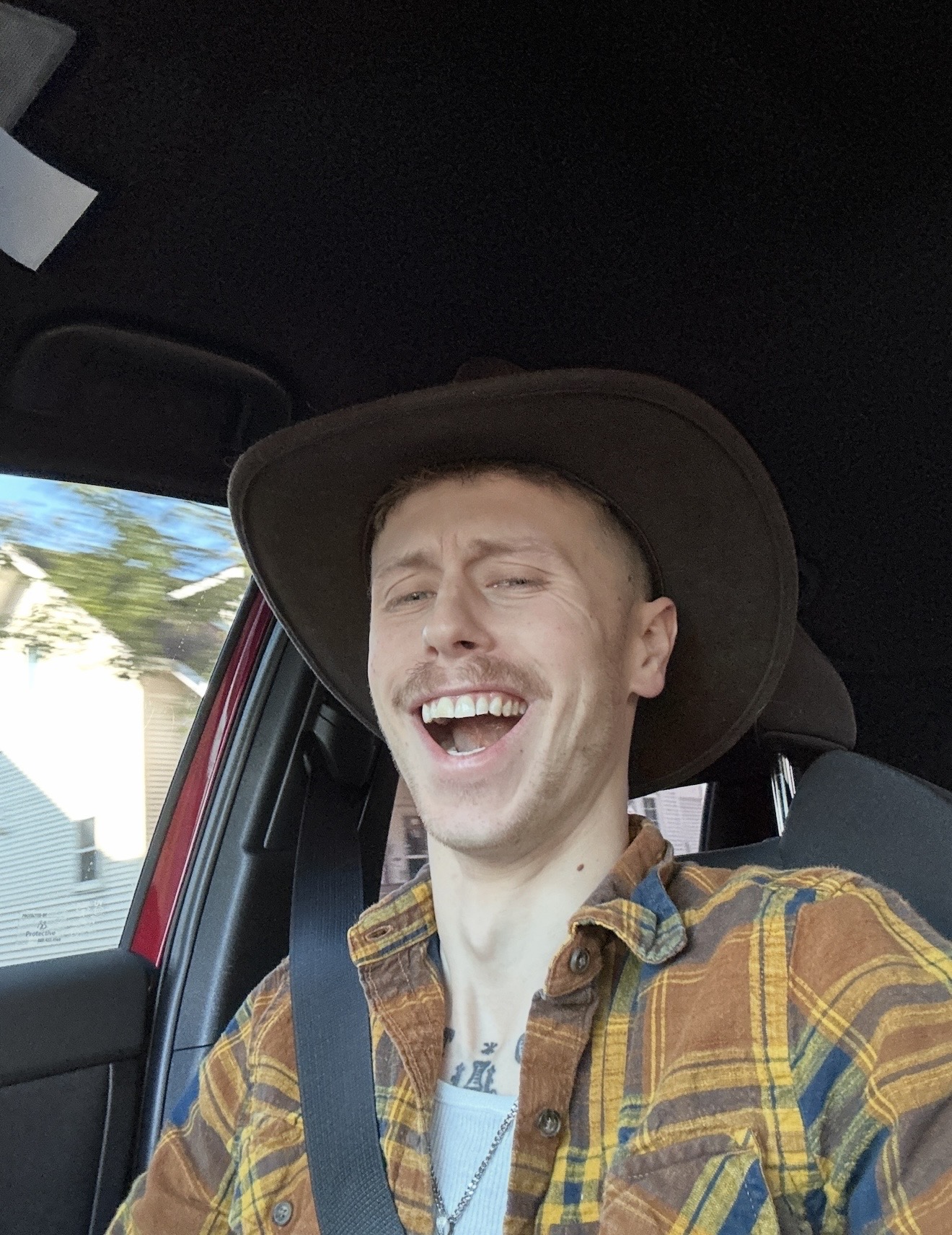 Logen laughing in a brown cowboy hat and plaid shirt